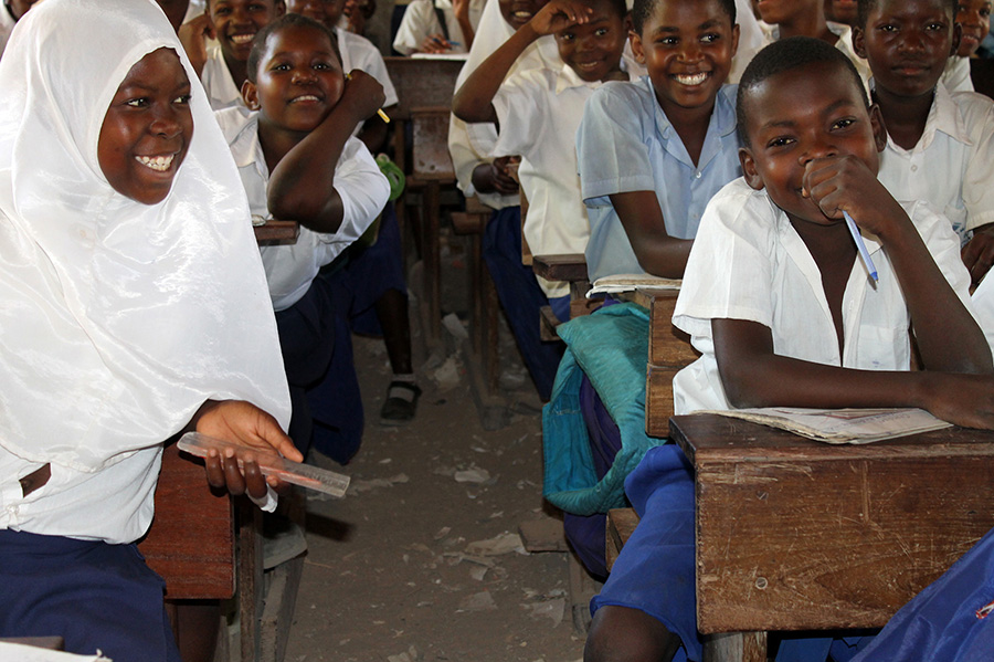Schüler der Mkuti-Grundschule in glücklicher Stimmung, nachdem sie Bücher erhalten haben, Projekt finanziert von African Palms, das Palmkreuze verkauft

