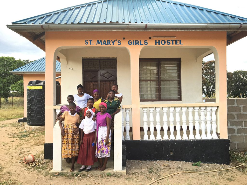 Mädchen, die vor dem von African Palms finanzierten Herbergsprojekt stehen und Palmkreuze verkaufen