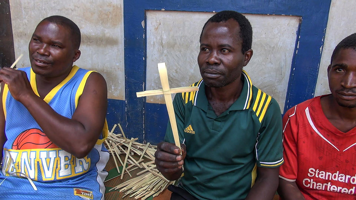 a man from Masasi Village at Tanzania holding a handwoven palm crosses after made it