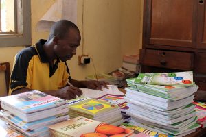 Officer Masasi recording books before distribution, project funded by African Palms selling palm crosses